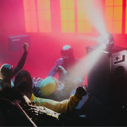 People dancing in a club with red and yellow lighting. Soundboks 4 and lightboks next to the table.