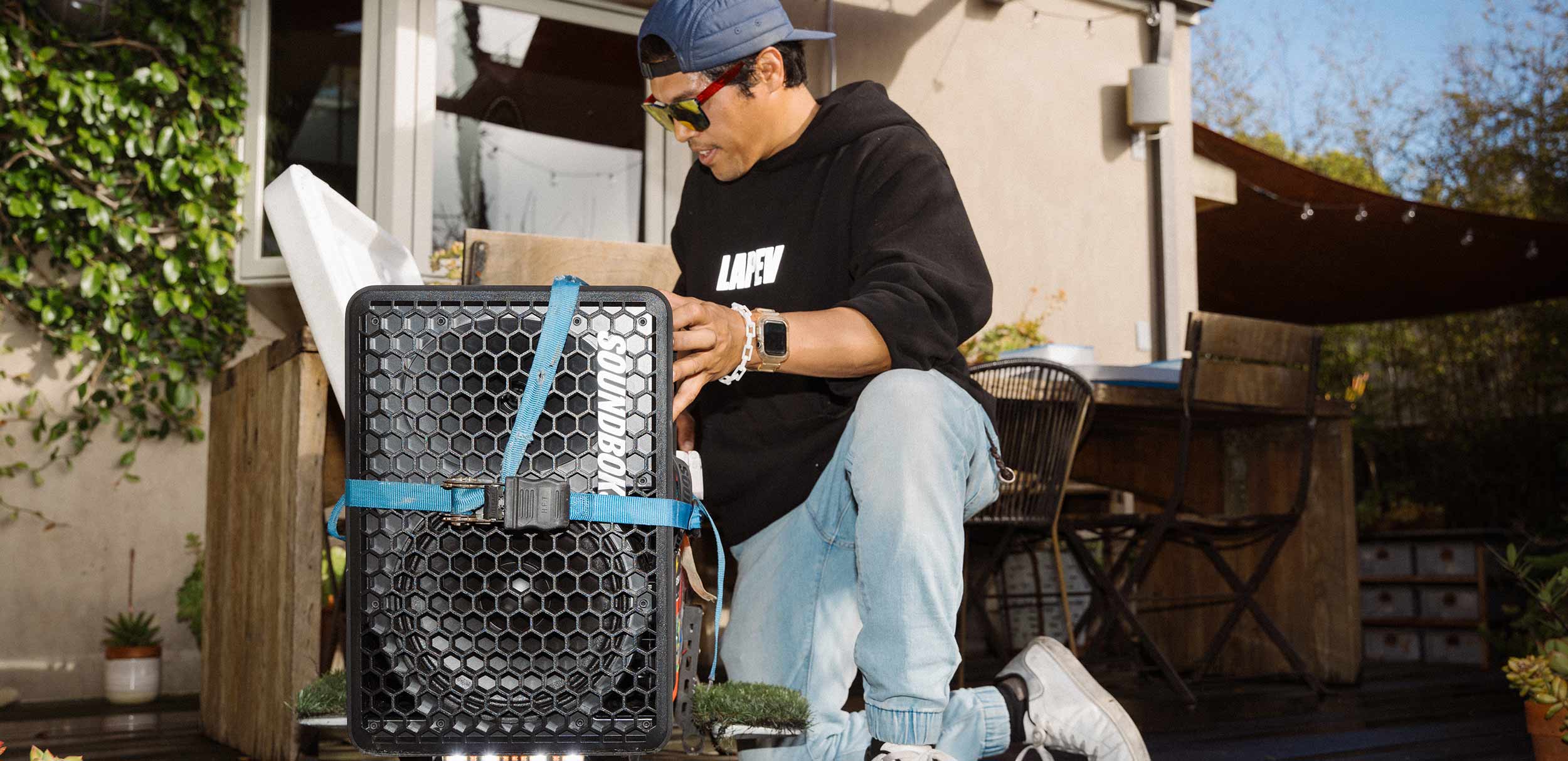 A person strapping a SOUNDBOKS Go onto a scooter