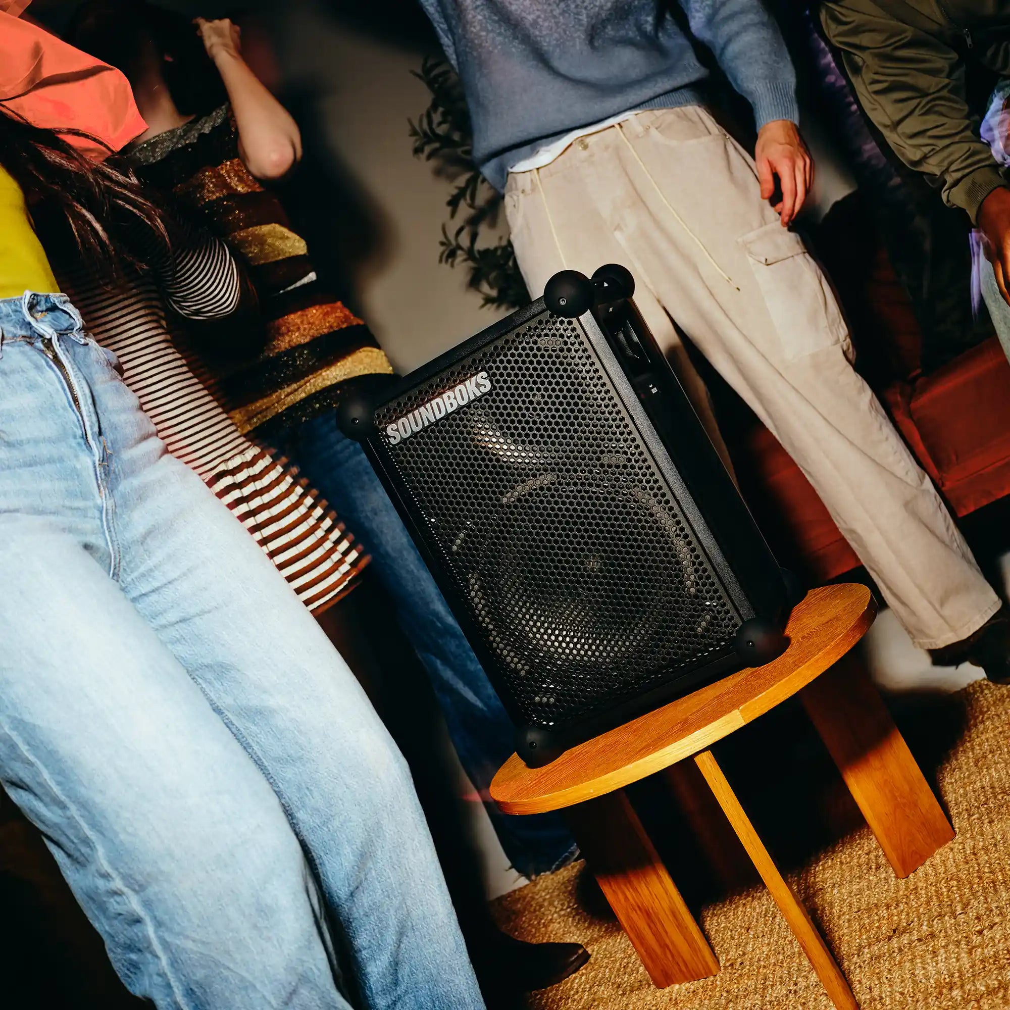 People dancing around the Soundboks Mix placed on a coffee table